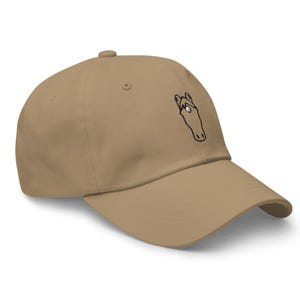 May include: A tan baseball cap with a black and white horse head design embroidered on the front.