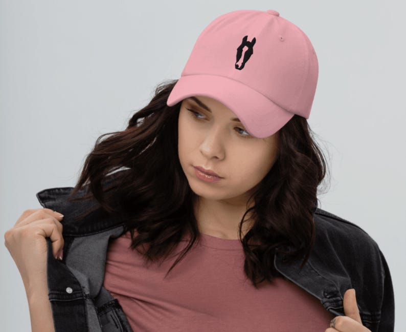 May include: A pink baseball cap with a black horse head design embroidered on the front.