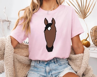 May include: A pink t-shirt with a brown horse head graphic. The horse has a white star on its forehead.