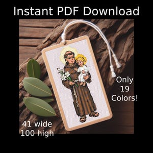 Könnte beinhalten: Ein Kreuzstichmuster mit dem heiligen Antonius, der das Jesuskind und weiße Lilien hält. Der Text lautet Instant PDF Download, Only 19 Colors!, 41 wide, 100 high. Das Design ist rechteckig und hat oben eine weiße Kordelschlaufe zum Aufhängen.