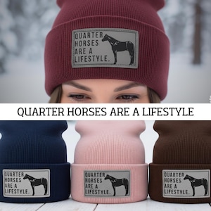Puede incluir: Gorros de punto en varios colores, incluyendo burdeos, azul marino, rosa y marrón. Cada gorro presenta un parche rectangular con la silueta de un caballo y el texto "QUARTER HORSES ARE A LIFESTYLE."