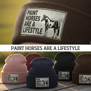 Pode incluir: Uma coleção de gorros em várias cores, cada um com um patch retangular com uma ilustração de cavalo e o texto "PAINT HORSES ARE A LIFESTYLE". As cores incluem rosa, azul marinho, preto e castanho.