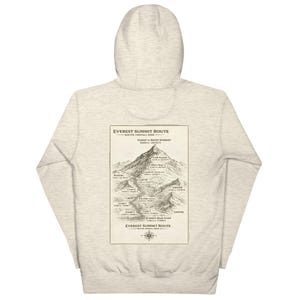 May include: A light gray hoodie featuring a detailed map of the Everest Summit Route on the back. The map is in a vintage style, with text indicating the route's key points and elevations in feet. The hoodie has a hood and long sleeves.