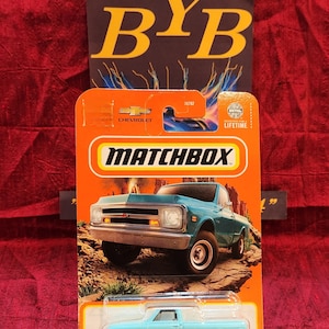 May include: A blue 1968 Chevrolet C10 pickup truck toy car in a Matchbox package. The package has a red, orange, and yellow background with the Matchbox logo and the words "Designed for a Lifetime".