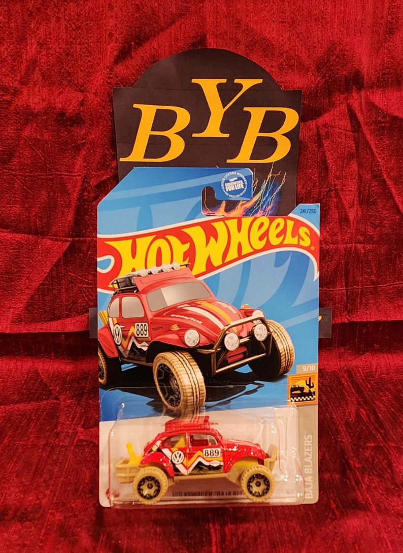 May include: A red Hot Wheels Baja Blazers die-cast toy car with a white and yellow stripe design. The car has a black grill, black headlights, and a black VW logo. The car is on a blue background with the words "Hot Wheels" in white letters. The car is numbered 241/250 and 9/10.