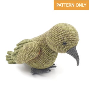 Op de afbeelding: Gehaakte vogel in groentinten, met een grijze snavel en poten en zwarte ogen. De vogel heeft een getextureerd uiterlijk. De tekst "PATTERN ONLY" staat in een oranje rechthoek rechtsboven.