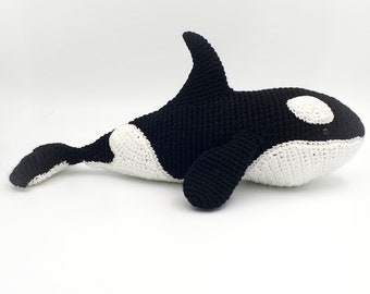 May include: Crochet pattern for a black and white orca whale amigurumi toy. The pattern is for a plush toy that is approximately 12 inches long.