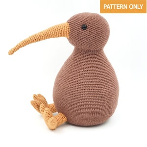 May include: A brown crocheted kiwi bird with an orange beak and feet. The kiwi is sitting on a white background.
