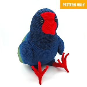 May include: A handmade crochet bird in shades of blue, red, and green. The bird has a red beak and feet, with black eyes. The text "PATTERN ONLY" is in a yellow rectangle in the top right corner. The bird is sitting.