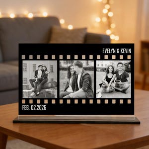 May include: A black photo display with three black and white images of a couple. The display has the text "EVELYN & KEVIN" and "FEB. 02.2026". The display sits on a wooden table.