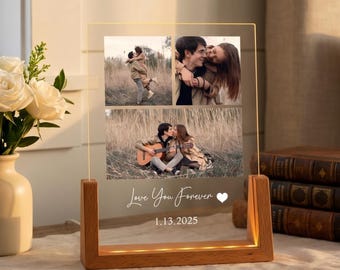 Op de afbeelding: Een heldere acryl fotodisplay met een houten voet. De display toont drie foto's van een stel en de tekst "Love You Forever" en de datum "1.13.2025". De voet heeft een warm licht.