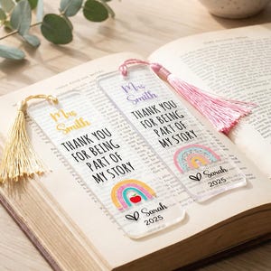May include: Two clear rectangular bookmarks with tassels. One has a gold tassel and yellow text, the other a pink tassel and purple text. Both feature the text "Mrs Smith THANK YOU FOR BEING PART OF MY STORY" with a rainbow, apple, and "Sarah 2025".
