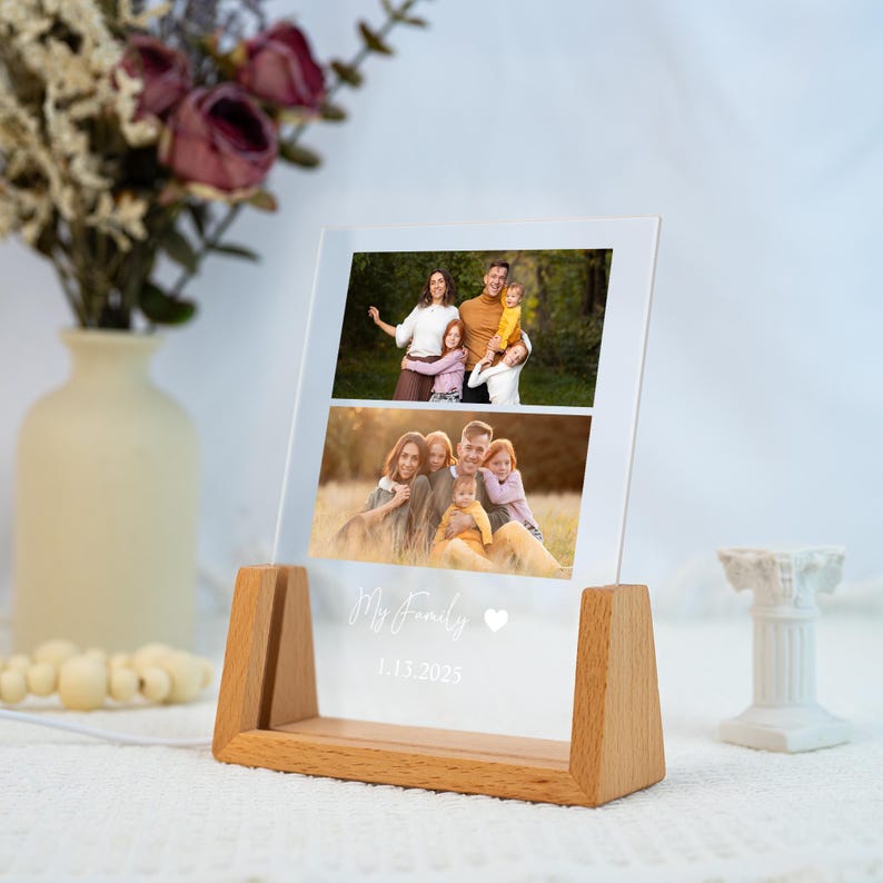 May include: A clear acrylic photo display with two family photos, set in a wooden base. The text "My Family" and the date 1.13.2025 are printed on the acrylic. A vase of flowers and a small white decorative column are in the background.
