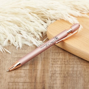 May include: A rose gold pen with a floral design and the name "Claire" engraved on the side.