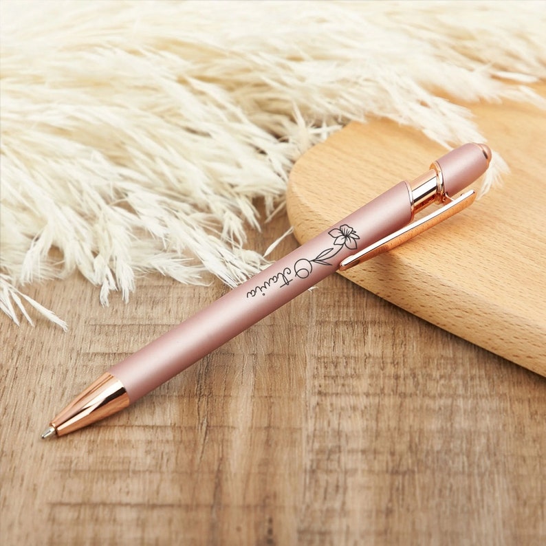 May include: A rose gold pen with a floral design and the name "Claire" engraved on the side.