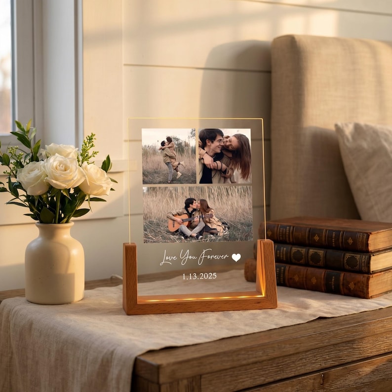 May include: A clear acrylic photo display with a wooden base. The display features three photos of a couple and the text "Love You Forever" and the date "1.13.2025". The base has a warm light.