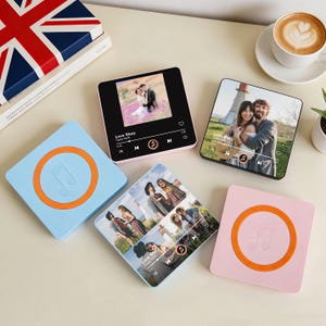 May include: A selection of square music players and coasters. The players show photos and music controls, in pink and black. Two coasters are light blue and pink, each with an orange music note design.