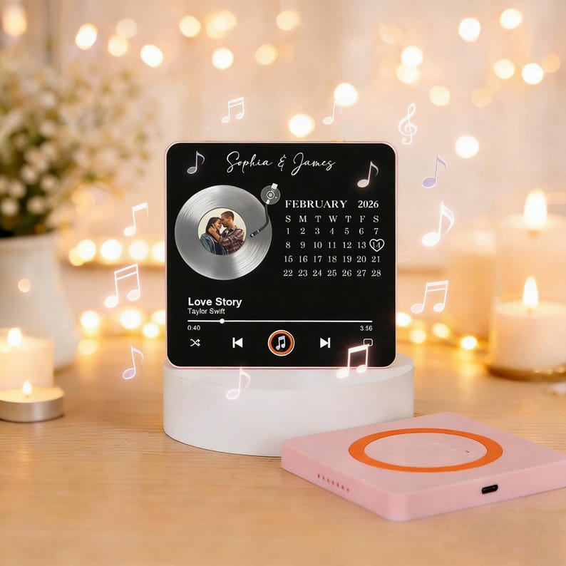 May include: A black square plaque with a photo, a record player graphic, and the text "Sophia & James" and "Love Story". The plaque also features a calendar for February 2026 and musical notes.
