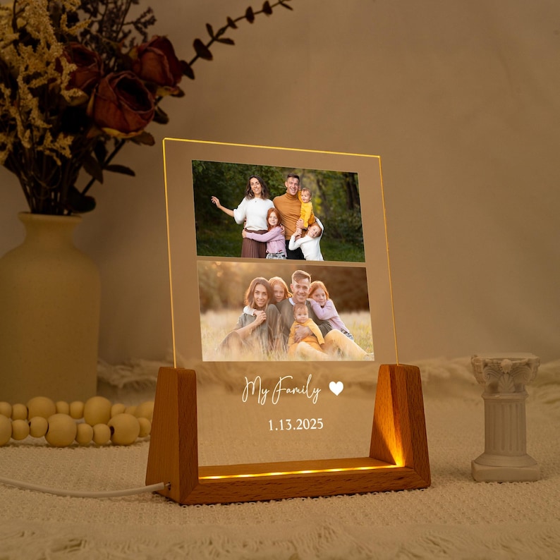May include: A personalised family photo night light. The rectangular acrylic panel displays two family photos and the text "My Family" with a heart symbol and the date 1.13.2025. The wooden base emits a warm glow.