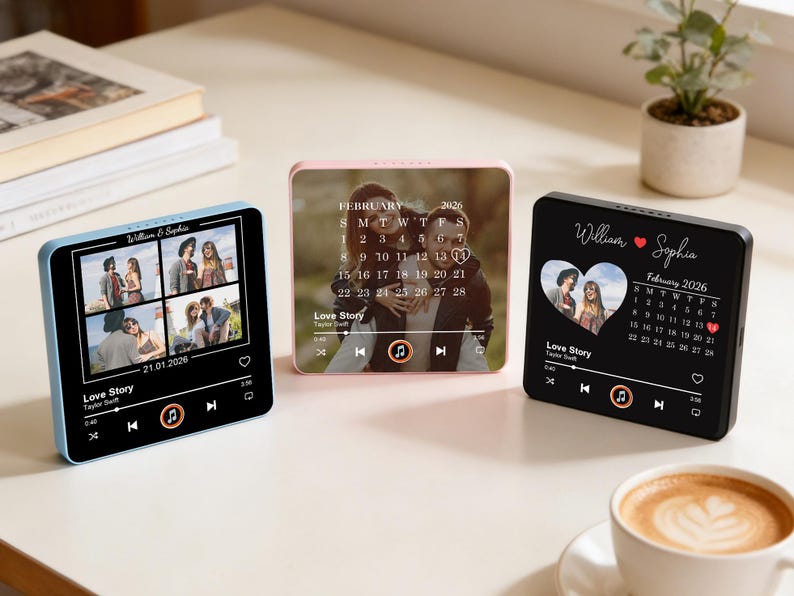 May include: Three square digital photo frames in blue, pink, and black. Each displays a couple's photo, a calendar, and music controls. The frames have the text "Love Story" and names. A cup of coffee sits in the foreground.