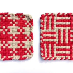 Könnte beinhalten: Zwei quadratische, gewebte Topflappen. Einer hat ein rotes und beiges Muster, der andere ein rotes und beiges geometrisches Design. Jeder hat eine Schlaufe zum Aufhängen. Die Topflappen sind aus gewebtem Material.