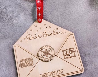May include: A wooden Christmas list envelope with a red ribbon and the words "Dear Santa" on the front. The envelope has a North Pole Special Delivery stamp and a Sleigh Mail stamp.
