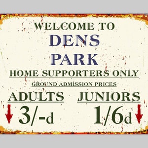 May include: A distressed metal sign with a cream background and a rusty brown border. The sign reads "WELCOME TO DENS PARK" in dark blue and green text. It displays "HOME SUPPORTERS ONLY" and admission prices for adults and juniors.