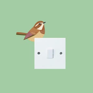 May include: A brown and white bird perched on a white light switch with a single toggle.