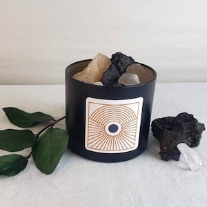 Puede incluir: Jarrón de vela negro con un diseño geométrico en la parte delantera. El jarrón está lleno de piedras blancas y marrones.