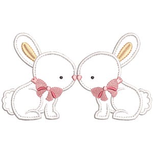 May include: Two white embroidered bunnies with pink bows facing each other. The bunnies have gold ears and are stitched in a simple style.