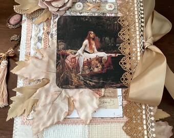Puede incluir: Un diario hecho a mano con una portada de collage. Presenta una pintura vintage, hojas de tela y una gran rosa. El diario está encuadernado con una cinta beige y adornado con encaje y elementos decorativos en tonos beige, rosa y crema.