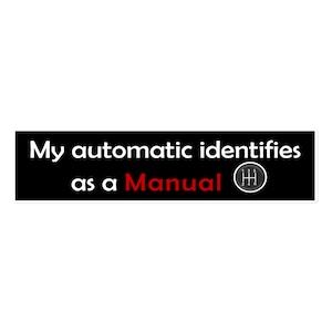 Puede incluir: Pegatina en blanco y negro con el texto "My automatic identifies as a Manual" en blanco y una perilla de cambio de marchas en blanco y negro con números rojos.