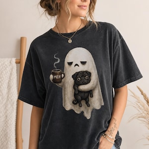 May include: A charcoal gray short-sleeve t-shirt featuring a graphic of a white ghost holding a brown mug with the text MEH and a black pug. The shirt has a faded, washed-out appearance with a crew neckline and a relaxed, boxy fit.