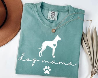 May include: Teal blue t-shirt with a white silhouette of a dog and the text "dog mama" with a white paw print below.