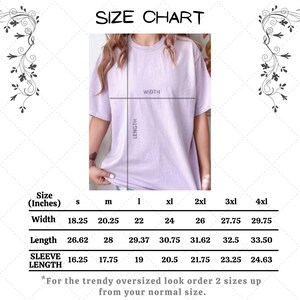 May include: A size chart for a lilac-colored t-shirt, with measurements in inches for width, length, and sleeve length. The chart includes sizes S through 4XL. The text at the bottom advises ordering two sizes up for an oversized look.