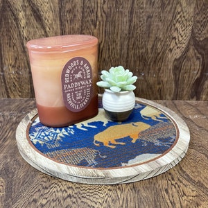 May include: A decorative wooden tray with a blue and orange patterned fabric insert, holding a candle and a small succulent in a pot. The candle is in a glass jar with a label that reads "Redwoods & Amber" and "Paddywax".