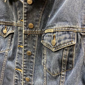 May include: A blue denim jacket with multiple silver metal buttons and a Star Blue Original label on the pocket.