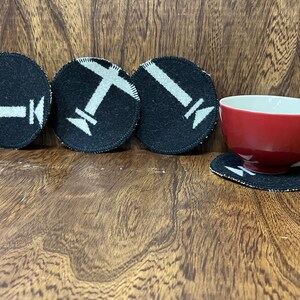 May include: Four black felt coasters with white airplane designs. A red ceramic mug sits on a coaster.