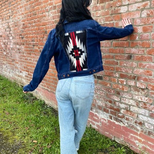 May include: A dark blue denim jacket with a red, white, and black geometric pattern on the back.