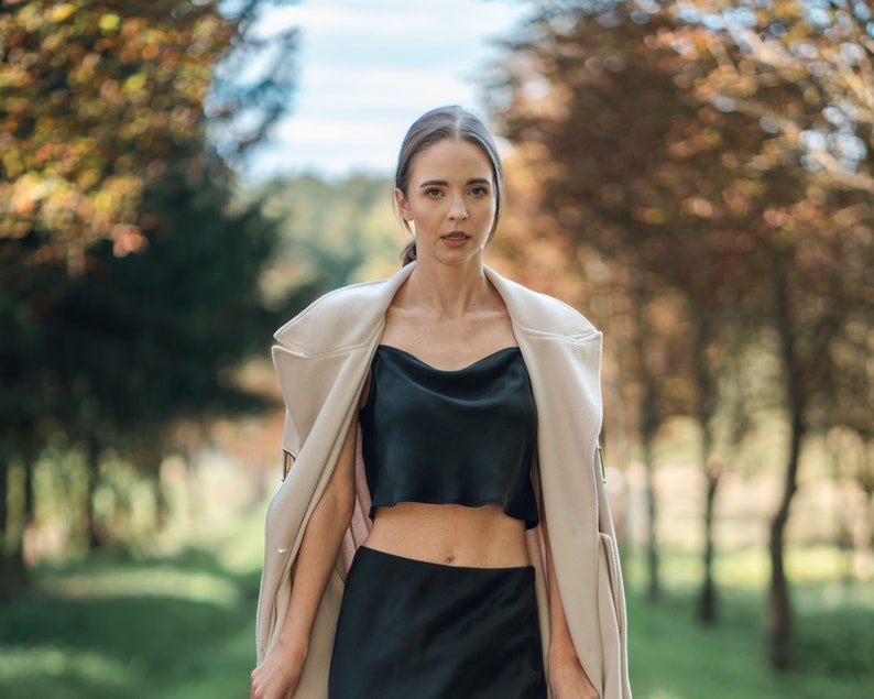 Woman wearing black silk cropped draped cowl neck camisole outdoors