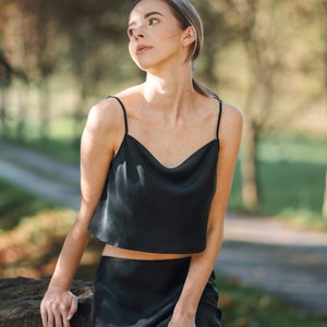 Woman wearing black silk cropped draped cowl neck camisole outdoors