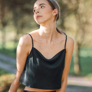 Woman wearing black silk cropped draped cowl neck camisole outdoors