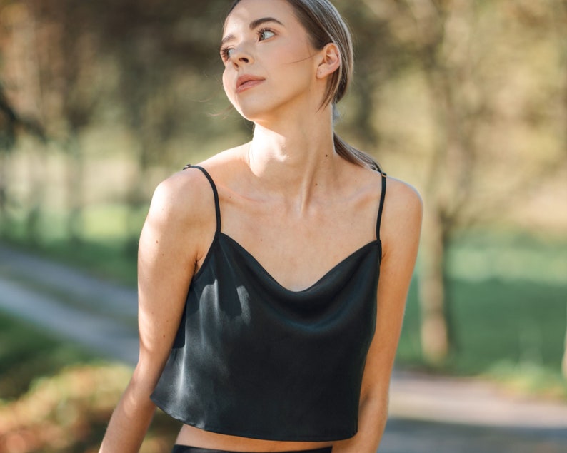 Woman wearing black silk cropped draped cowl neck camisole outdoors