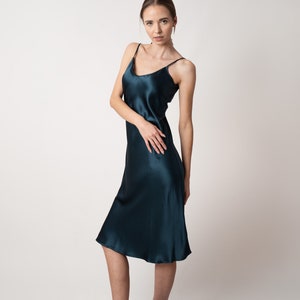 Beautiful woman wearing  navy blue silk slip bias cut dress or nightie in studio