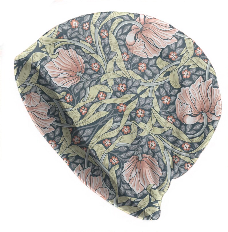 May include: A beanie hat with a floral pattern. The hat features large, stylized pink flowers, small orange flowers, and green leaves on a dark gray background. The design is reminiscent of vintage botanical illustrations.