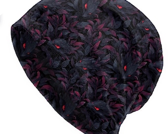 May include: A black beanie hat featuring a repeating pattern of dark leaves and red glowing eyes. The design creates a spooky, fantasy theme. The hat is made of a soft material and is suitable for cold weather.