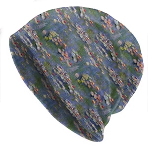May include: A beanie hat with a Monet-inspired water lilies pattern. The design incorporates blue, green, and yellow tones, giving an impressionistic appearance. The hat is made of a soft fabric, suitable for cooler temperatures.