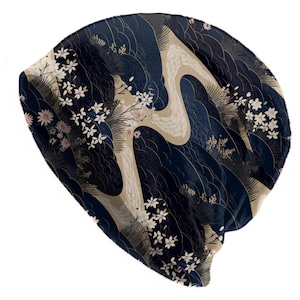 Può includere: Un berretto blu navy con un design di ispirazione giapponese. Il berretto presenta un motivo a onde, accenti beige e dettagli floreali bianchi e rosa. Il berretto è realizzato in un materiale morbido e confortevole.