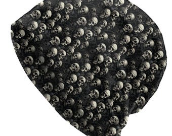 May include: Black beanie hat featuring a repeating pattern of white skulls. The skulls are detailed and cover the entire surface, creating a gothic aesthetic. The hat is made of a soft material, suitable for colder weather.