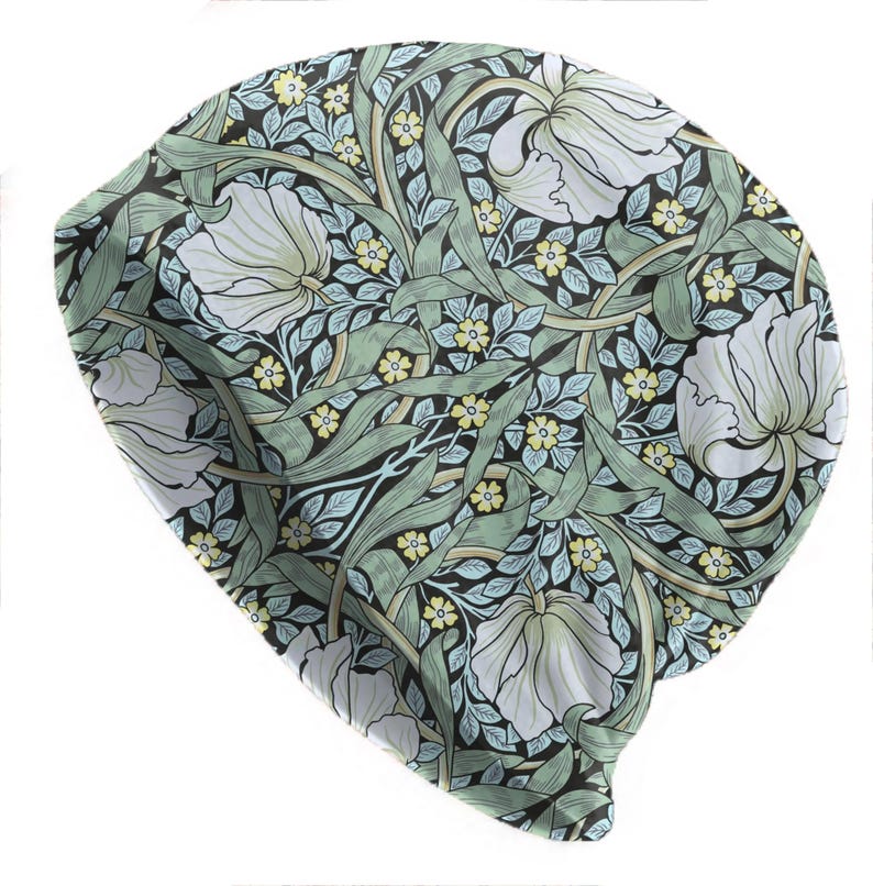May include: A beanie hat with a floral pattern. The hat features a repeating design of white flowers, green leaves, and small yellow blossoms on a black background. The beanie is made of a soft, flexible material.